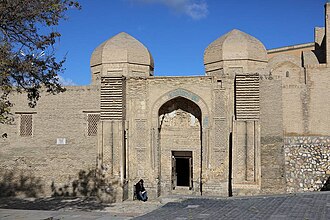 An entrance into a wall-like structure with two domes on top.